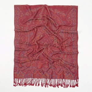 Detailed close-up of red paisley jacquard fabric and fringe trim on long scarf