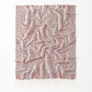 Detailed view of paisley jacquard pattern and white tassels on soft pink shawl
