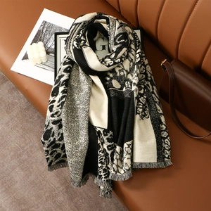 Close-up of thick leopard print scarf with herringbone weave and fringe on leather sofa