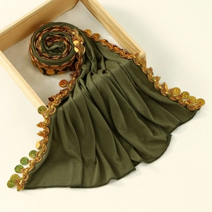 Detail of olive green hijab with gold sequin trim and handmade beaded fringe accents