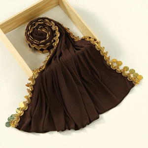 Detail of dark brown hijab featuring shimmering gold sequins and ethnic coin fringe edges