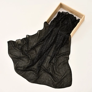 Macro shot of black chiffon scarf with silver glitter sequins in a light wooden box