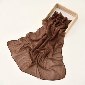 Detail of dark brown semi-transparent scarf with silver glitter in a wooden gift box