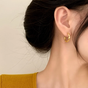 Elegant gold textured C-shaped stud earrings with irregular pleated surface design