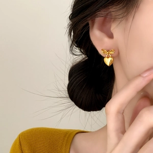 Elegant gold bow heart earrings shown on model for a stylish minimalist commute style