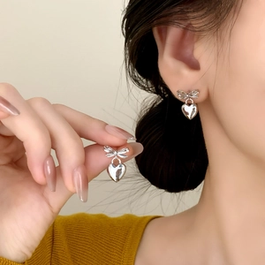 Silver bow heart drop earrings for women with mirror finish on elegant model shot