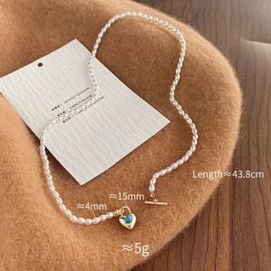 Détail du collier en perles d'eau douce avec pendentif cœur turquoise et fermoir T