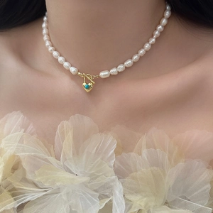 Gros plan du collier de perles avec pendentif cœur en turquoise dorée et fermoir à bascule