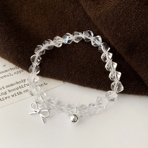 Elegant beaded bracelet featuring clear faceted beads and a silver bow and bell charm