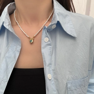 Détail du collier de perles d'eau douce avec pendentif cœur doré et incrustation turquoise