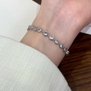 Minimalist silver tennis bracelet with round cubic zirconia stones worn on female wrist
