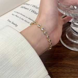 Luxurious gold bezel-set crystal bracelet on wrist with elegant lifestyle background