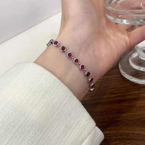 Elegant silver bracelet with 12 round-cut red zircons worn against a stylish white sleeve