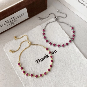 Adjustable gold and silver pull bracelets with pink round gemstones on textured paper