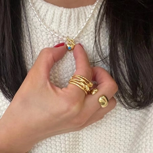 Gros plan du collier en perles d'eau douce avec pendentif cœur et bagues dorées