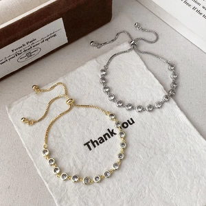 Detail of adjustable gold and silver bracelets with round stones on a white paper background