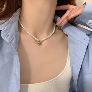 Gros plan du pendentif cœur turquoise sur collier perles d'eau douce sur modèle
