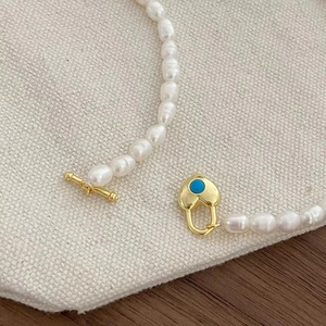Détail du pendentif cœur turquoise avec fermoir doré sur collier de perles d'eau douce
