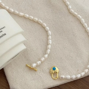 Détail du collier de perles d'eau douce avec fermoir cœur doré et pierre turquoise