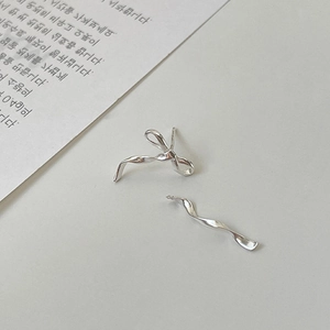 Detailed view of silver bow and twisted bar asymmetric stud earrings on minimalist card