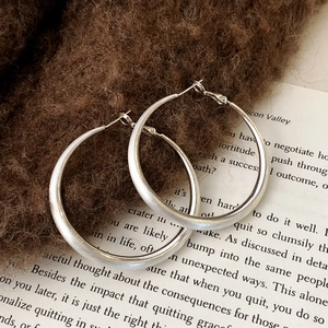 Macro detail of silver geometric brushed metal hoop earrings on vintage book background