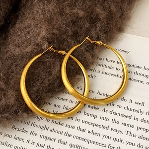 Detail of large gold hoop earrings with matte brushed finish on soft knit fabric