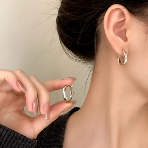 Boucles d'oreilles torsadées en argent sur modèle avec un design en métal élégant épuré