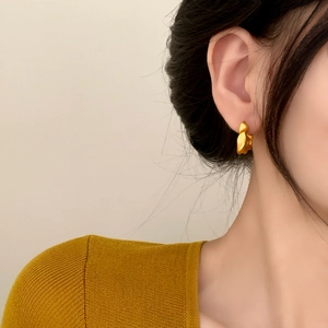 Minimalist matte gold irregular earrings with organic art style worn by a fashion model