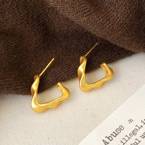 Macro detail of matte gold wavy hoop earrings with artistic irregular twisted design