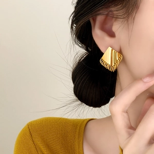 Elegant gold geometric earrings with delicate fringe tassels worn by a model