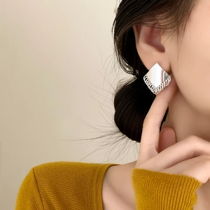 Minimalist silver geometric tassel earrings worn by a model in a high-fashion studio shot