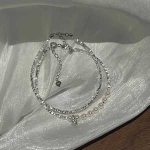 Detail of silver S925 double-layer bracelet with pearls and heart charm on silk fabric