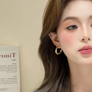 Minimalist matte gold twisted hoop earrings worn by a model for a chic retro fashion look