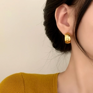 Minimalist wide C-shaped gold earrings with brushed diagonal texture on model ear