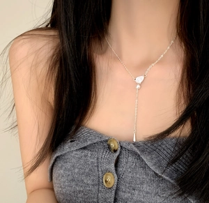 Close-up of elegant Y-shaped silver necklace with teardrop zircon tassel on a model