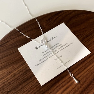 Elegant Y-shaped necklace with teardrop zircon and pearl on a dark wooden background