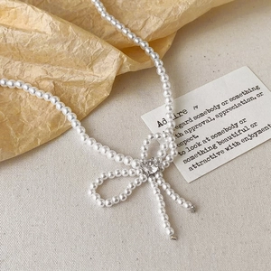 Elegant French style pearl necklace featuring a woven pearl bow pendant with a crystal center
