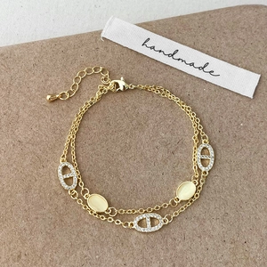 Golden double-layer chain bracelet featuring cat eye stones and cubic zirconia
