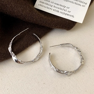 Macro detail of irregular lava texture on silver-tone hoop earrings for women