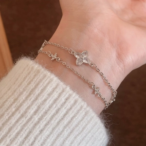 Elegant silver double-layer clover bracelet with zircon crystals on a woman's wrist
