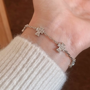 Minimalist silver cross bracelet with shimmering zircon stones on a model's wrist