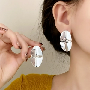 Minimalist silver oval stud earrings with chain detail shown on a female model