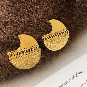 Macro detail of gold geometric earrings with textured mesh and smooth crescent design