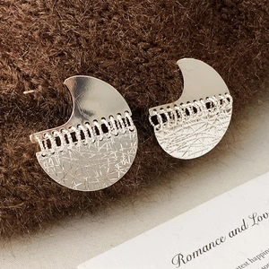 Detailed macro shot of silver geometric earrings with chain fringe on knit texture