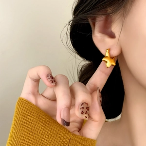 Minimalist gold star earrings with a polished finish shown on model for a trendy look