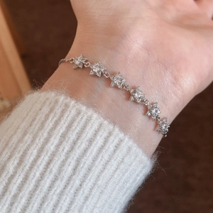 Elegant silver star bracelet with sparkling zircon stones worn over a cozy white sweater