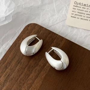 Macro shot of matte silver U-shaped earrings with brushed metal texture and S925 stamp