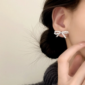 Orecchini a perno eleganti a forma di fiocco di perle bianche indossati da una modella
