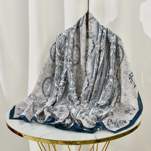 Detail of silk-texture paisley shawl with blue borders on white marble table decor