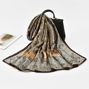 Detail of silk-like paisley print scarf elegantly draped over a black handbag
